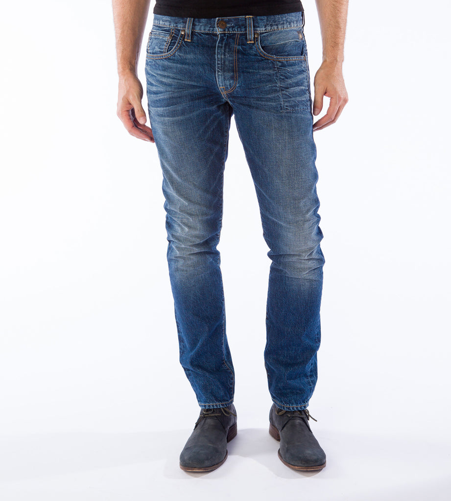 A man wearing a slim fit, vintage medium blue hemp blend jeans and dark shoes by HempBlue